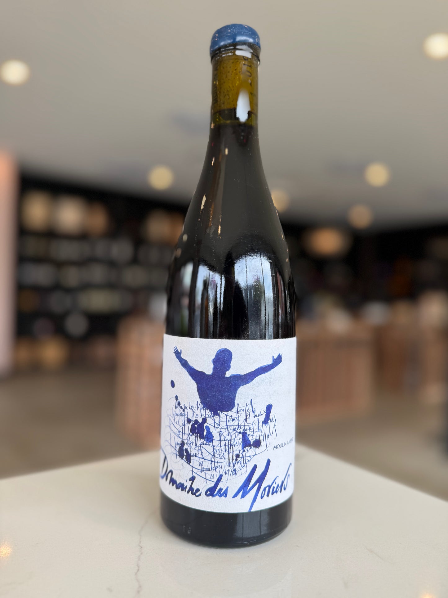 Wine bottle with a blue label featuring a graphic design on a blurred background