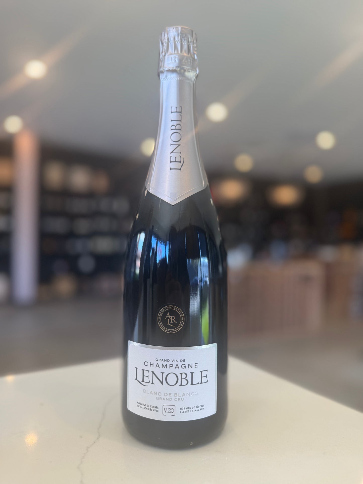 Bottle of Lenoble champagne on a reflective surface with a blurred background