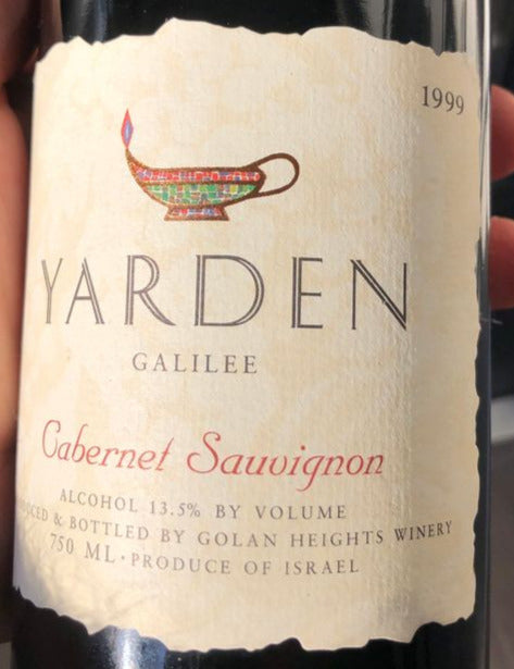 Yarden Cabernet Sauvignon wine bottle label from 1999 held by a hand.